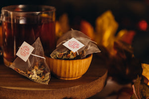 Glass mug of herbal tea with tea bags and autumn leaves